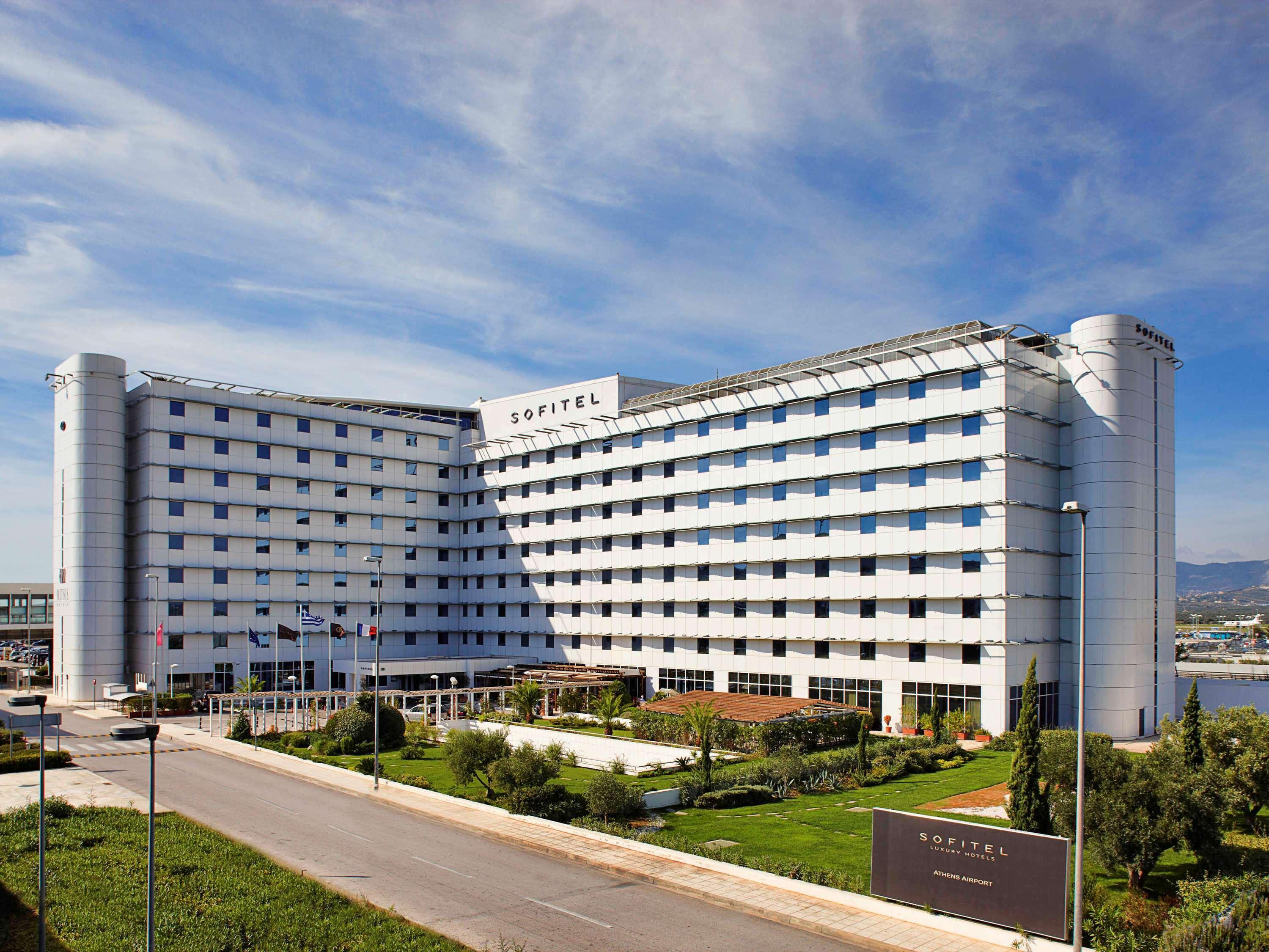 Sofitel Athens Airport Hotel Spata  Bagian luar foto The photo shows a modern hotel building with a distinct architectural design. It is a multi-story structure featuring a combination of glass and concrete elements, characterized by a large facade that has a series of windows. The hotel appears to be 