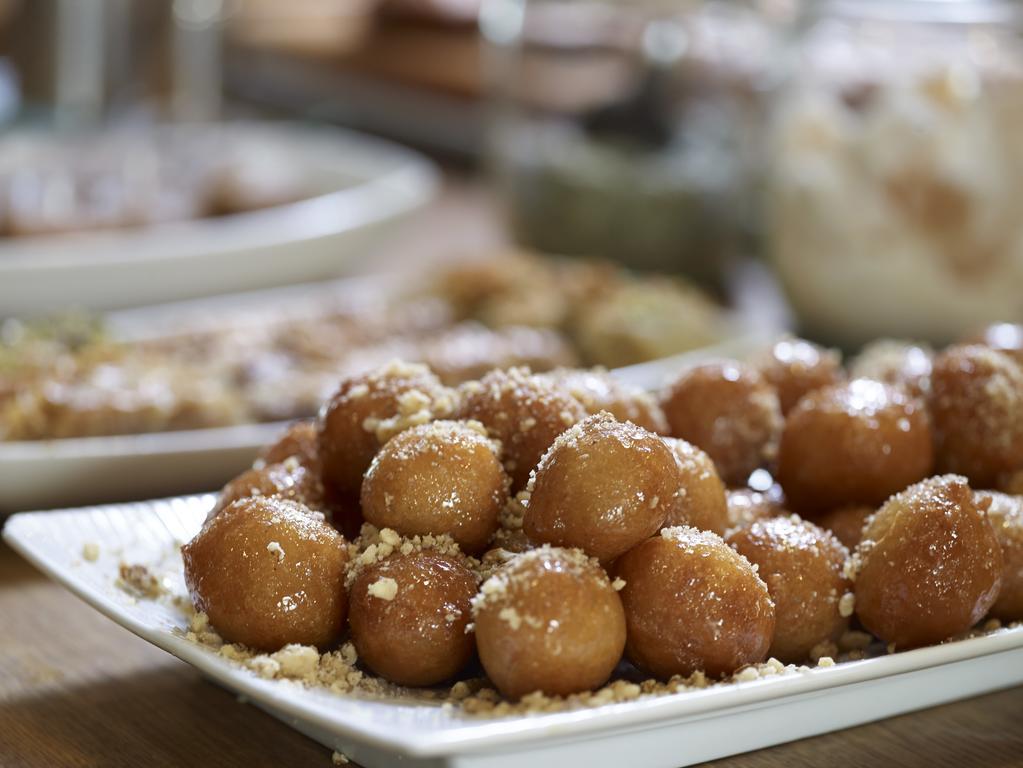 Sofitel Athens Airport Hotel Spata  Bagian luar foto The photo shows a plate of small, round, golden-brown sweets, which appear to be deep-fried dough balls. They are coated in a layer of granulated sugar or crushed nuts, giving them a sweet and crunchy appearance. In the background, there are other di